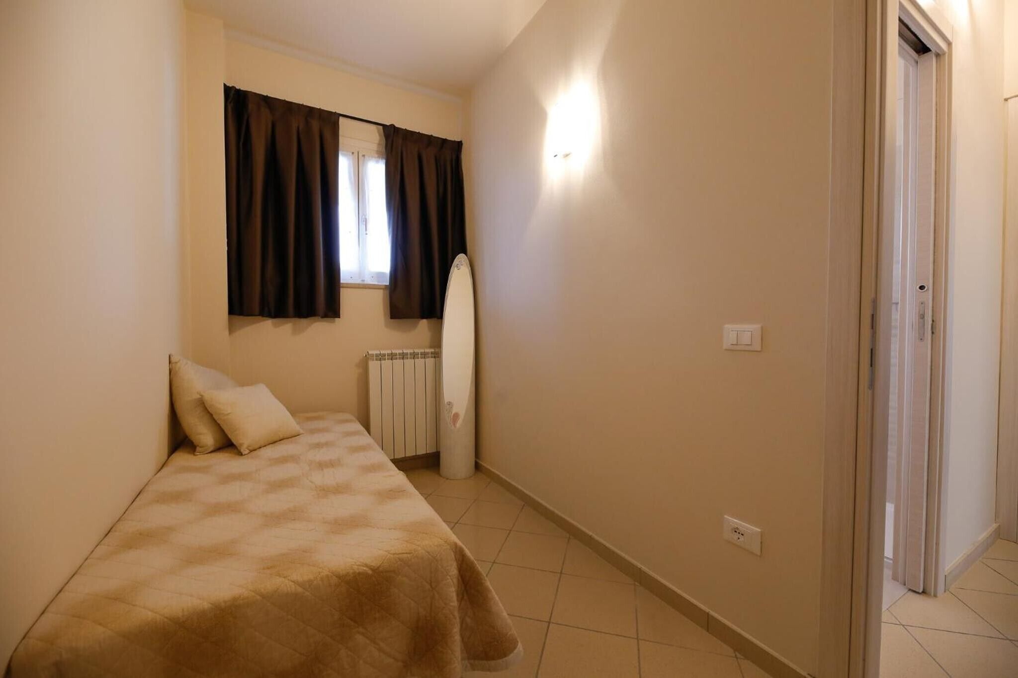Un dormitorio con una cama, un radiador, una ventana con cortinas y una puerta.