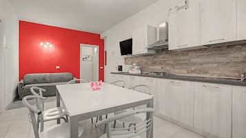 Una cocina moderna con armarios blancos, encimera gris y pared de acento roja.