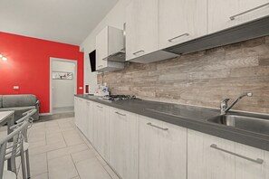 Een moderne keuken met een roestvrijstalen spoelbak, een gasfornuis en lichtkleurige kastjes.
