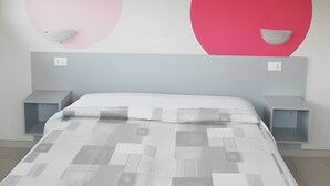 Una camera da letto con un letto, due comodini e una parete decorata con motivi circolari.