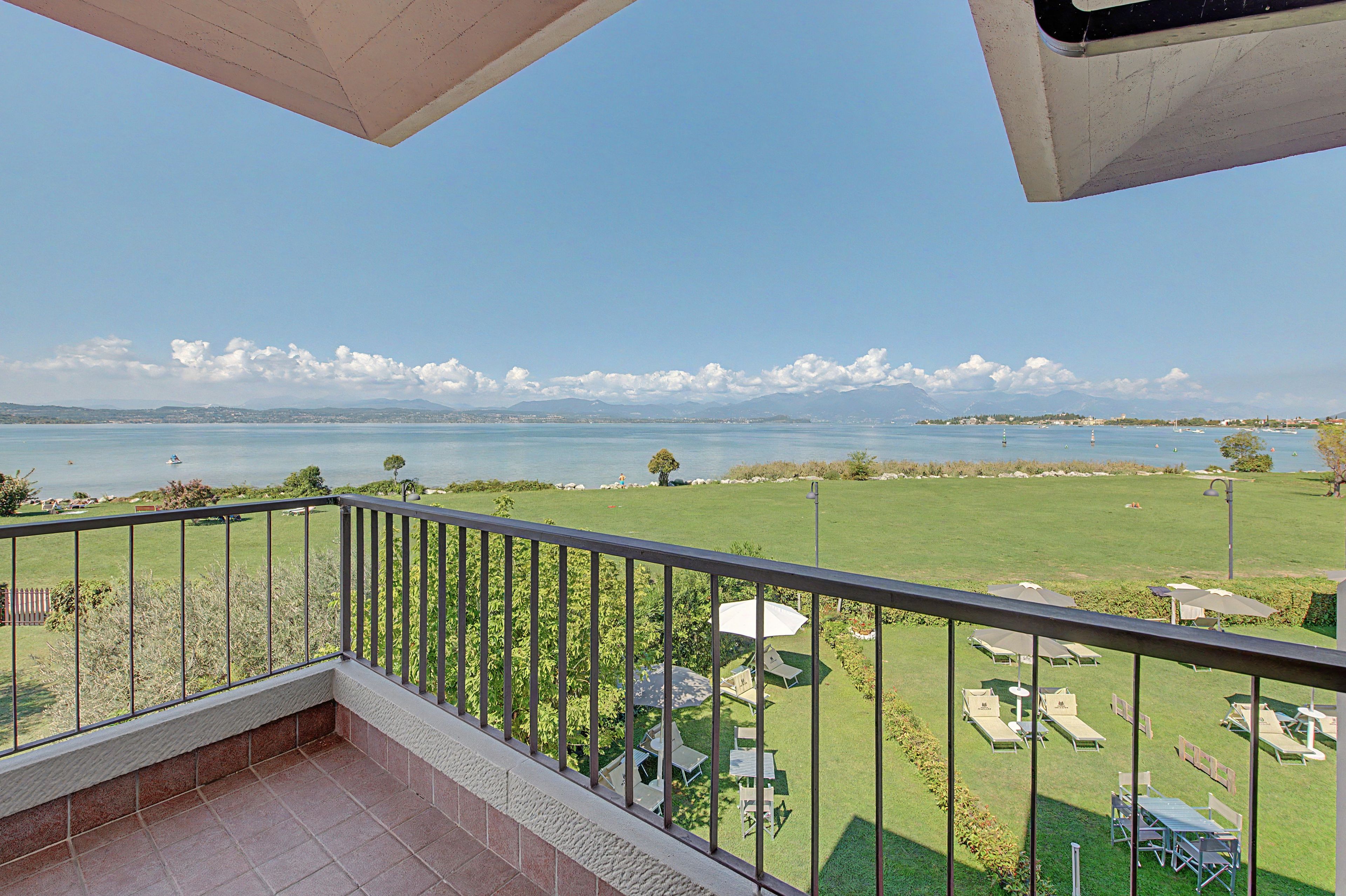 Ein Balkon mit Blick auf eine Wiese und ein Gewässer.