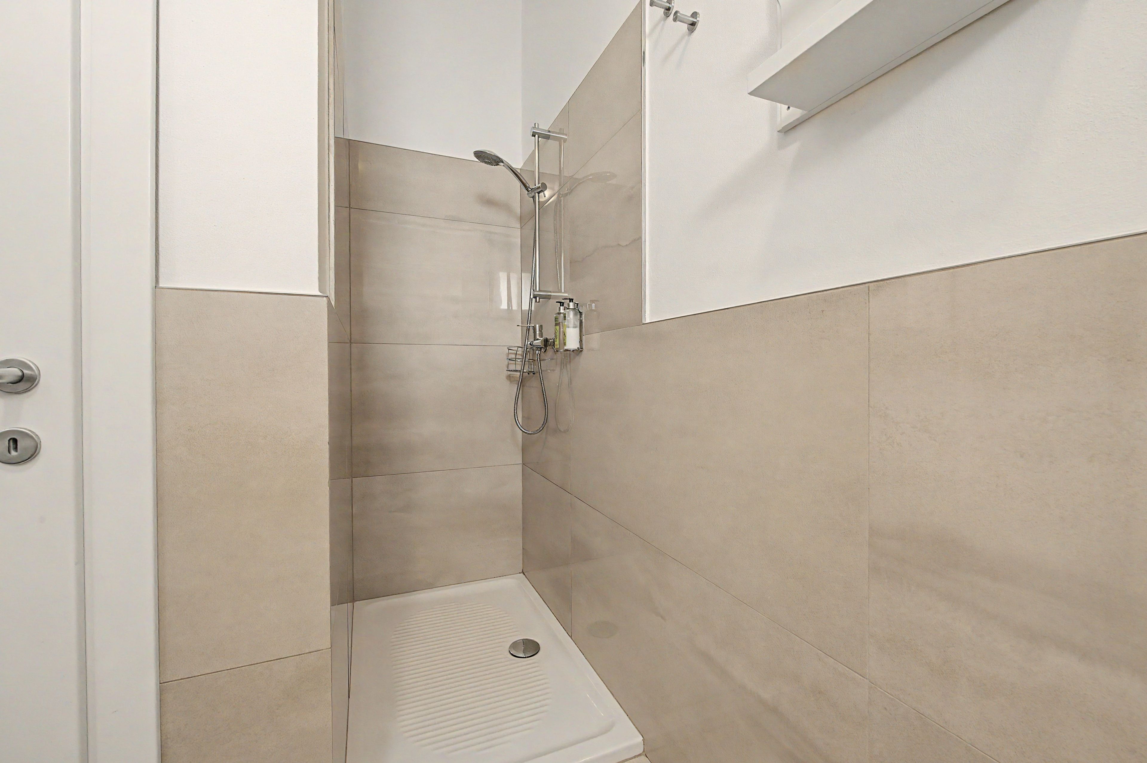 Une petite salle de bain moderne, équipée d’une douche, de toilettes et d’un miroir.
