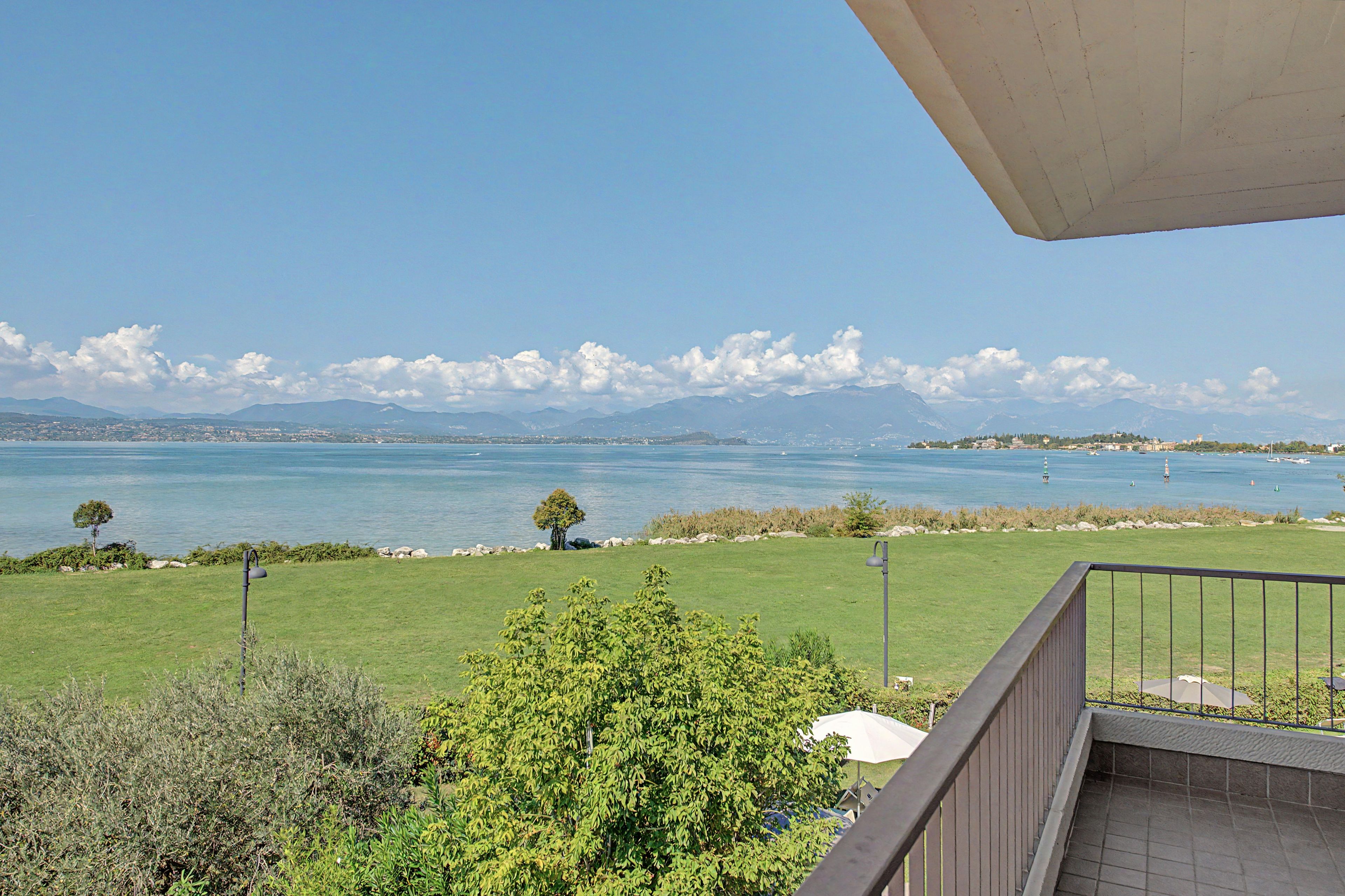 Ein Balkon mit Blick auf einen See, Berge und eine entfernte Stadtlandschaft.