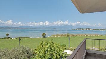 Ein Balkon mit Blick auf einen See, Berge und eine entfernte Stadtlandschaft.