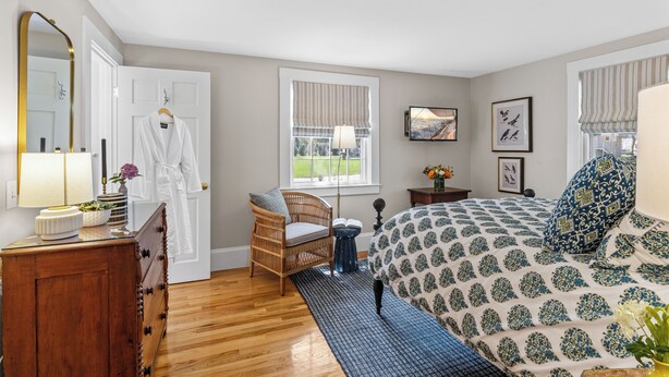 Quarto com cama, cômoda, cadeira e janela com vista.
