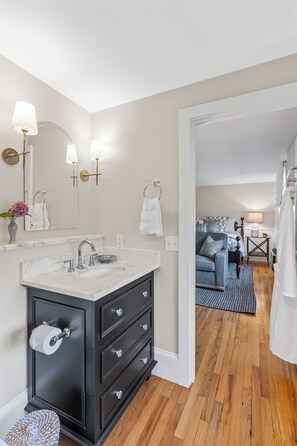 Un baño moderno con lavamanos de mármol, muebles oscuros y un espejo con apliques de pared.