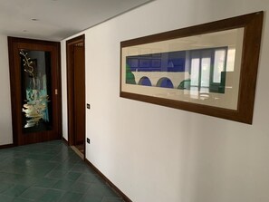 A hallway with a framed artwork on the wall, a door with a decorative glass panel, and a tiled floor. - Spacious apartment in the historic center of Fondi (Fondi)