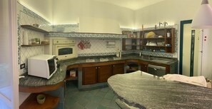 Een compacte keuken met een magnetron, oven en een geïntegreerde vaatwasser. Er zijn houten kastjes en een granieten aanrecht.