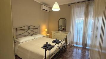 Una camera da letto con un letto, lampada da comodino, comò, specchio e condizionatore d'aria.
