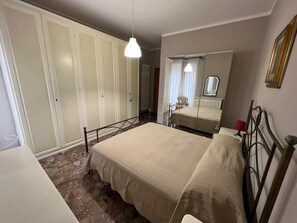 Een slaapkamer met een bed, een kledingkast, een spiegel en een hanglamp.