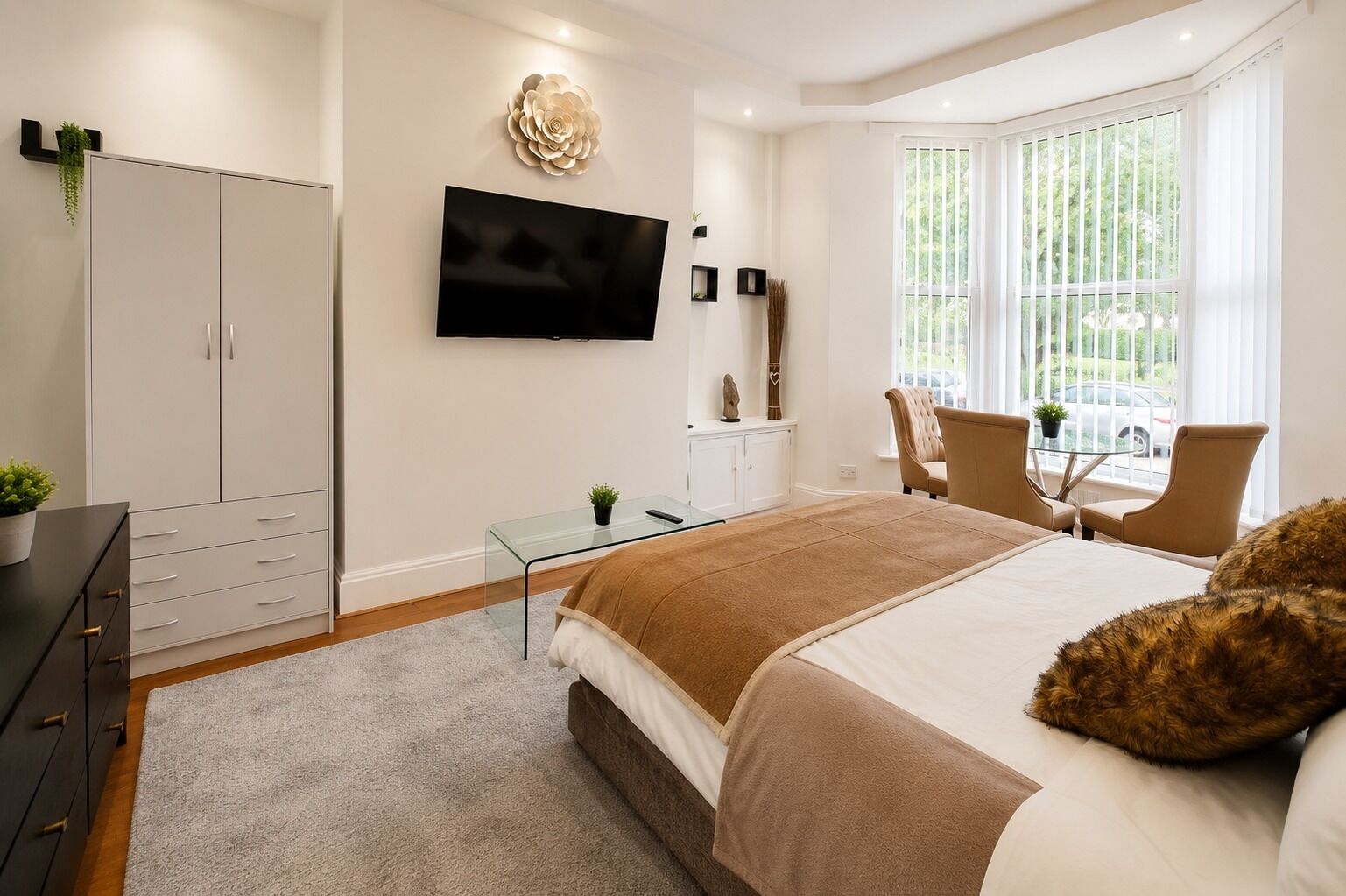 A modern bedroom with a bed, a TV, a desk, and a chair.