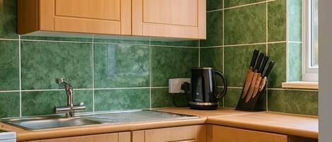 A kitchen with wooden cabinets, a sink, a coffee maker, and a window.
