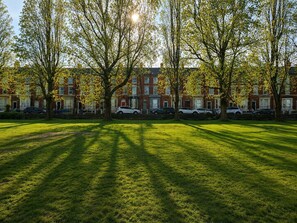 A grassy area with trees and parked cars in front of a row of red brick townhouses. - Ground floor, Private, Free Parking, Park, Views (Liverpool)