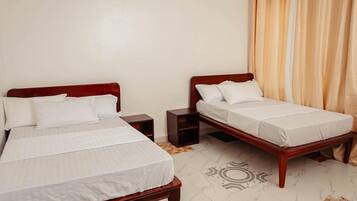 Quarto de hotel com duas camas de solteiro, mesa de cabeceira e um tapete estampado.