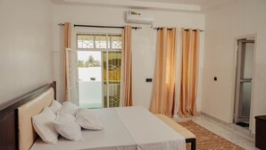 Quarto com cama, janela com cortinas, ar condicionado e vista para o exterior.