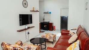 Uma sala de estar com televisão de tela plana, lareira, sofá e mesa de centro.