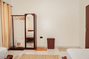 Habitació d'hotel amb un llit, un armari amb mirall, un petit safataire i una catifes amb dibuixos.