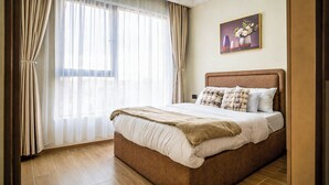Une chambre à coucher avec un grand lit, des rideaux, un tableau et un plancher en bois.