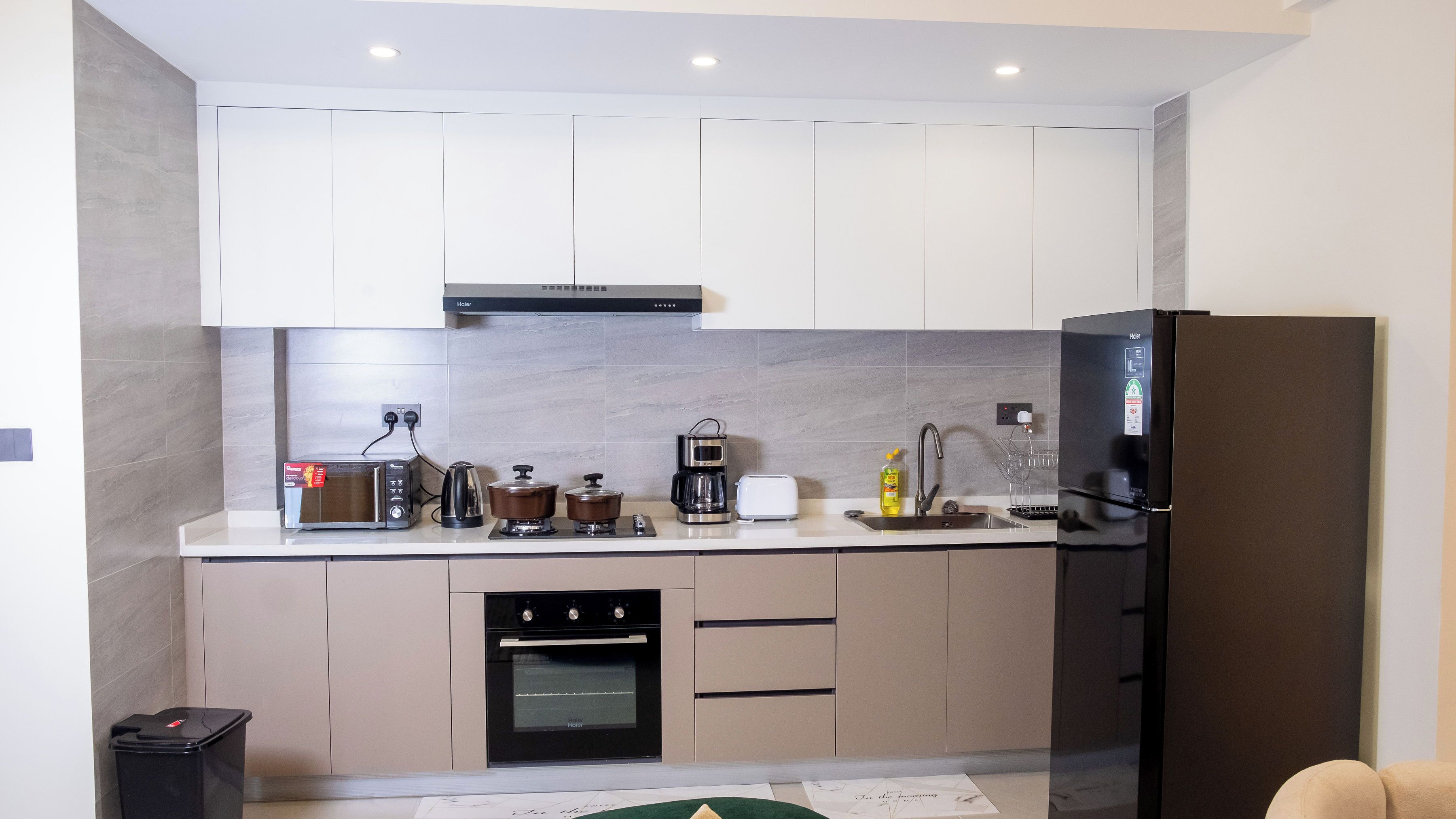 A modern kitchen with a built-in oven, a coffee maker, a toaster, and a refrigerator.