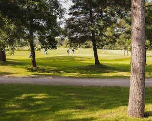 Campo de golf con un sendero despejado, árboles y una vista distante de jugadores.