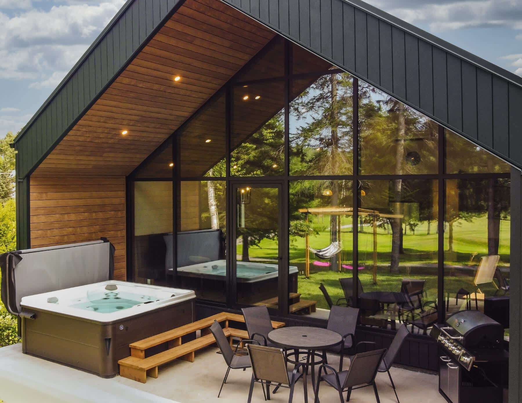 Un espace moderne aménagé à l’extérieur avec un jacuzzi, des sièges et un barbecue.