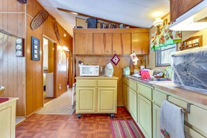 A compact kitchen with wooden cabinets, a microwave, and a sink.