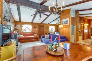 Living and dining space with wood-paneled walls and exposed ceiling beams.