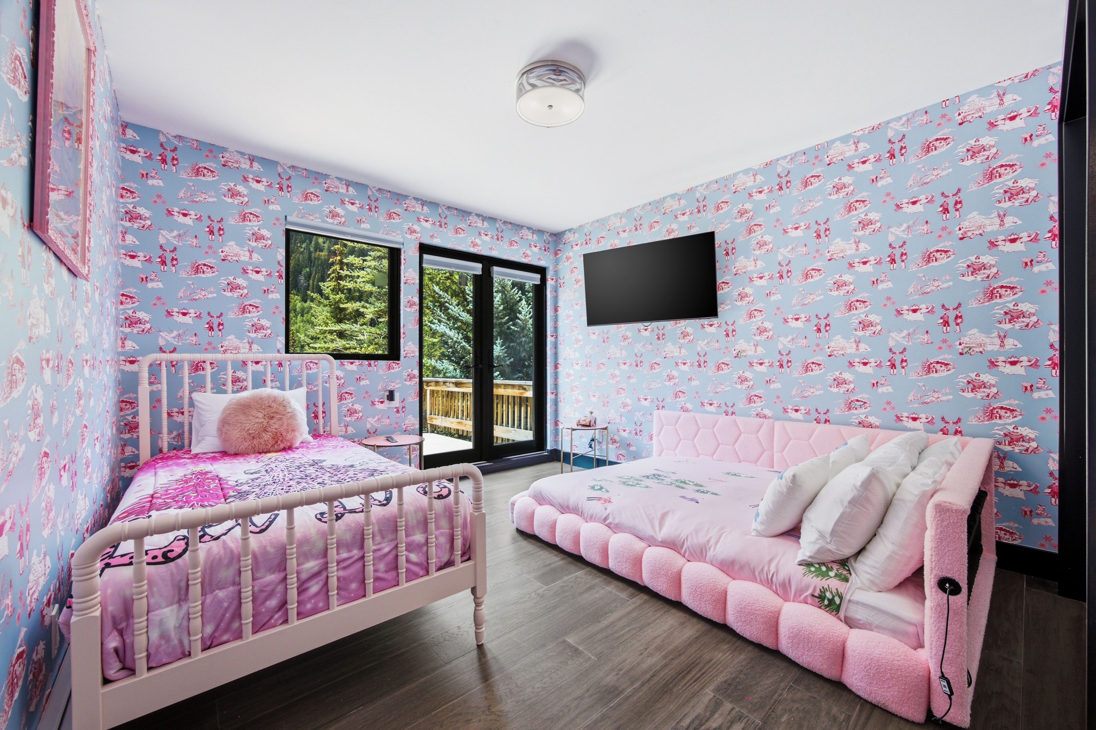 A bedroom with a bed, a window, a TV, and a view of the outdoors.