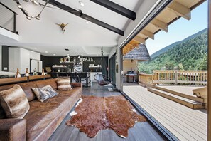 Een modern interieur met een leren bank, een kussen van ruitjeskoeienhuid en een keukenhoek.
