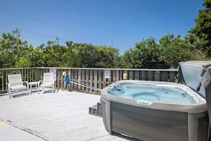 A wooden deck with a hot tub, a bench, and a signboard. - 2 min Walk to Beach w Ocean Views, Pool, Game Room (Nags Head)