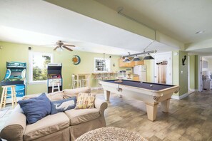 A pool table in a room with a sofa, a ceiling fan, and a sun decoration on the wall. - 2 min Walk to Beach w Ocean Views, Pool, Game Room (Nags Head)
