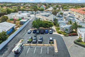 A parking lot with several cars and a bus, surrounded by modern buildings with flat roofs and a clear sky. - Casa Atardi – Your tropical home away from home in Curaçao (Willemstad)