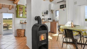 Een gezellig interieur met een houtkachel, een eethoek en een keuken met moderne apparatuur.