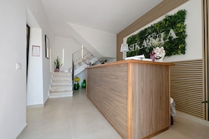 Un espace d’accueil comprenant un comptoir de réception en bois, un escalier et un panneau fixé au mur.