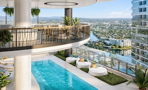 A rooftop pool area with a view of the cityscape, surrounded by greenery and modern seating. - Sage Above the Sea - Ocean Views (Broadbeach)