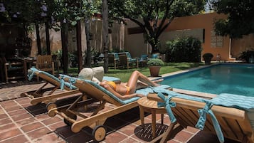 A poolside area with lounge chairs and a person relaxing.