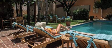 Area piscina con lettini e una persona che si rilassa.