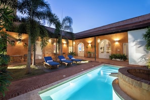 A pool area with lounge chairs and a brick patio.