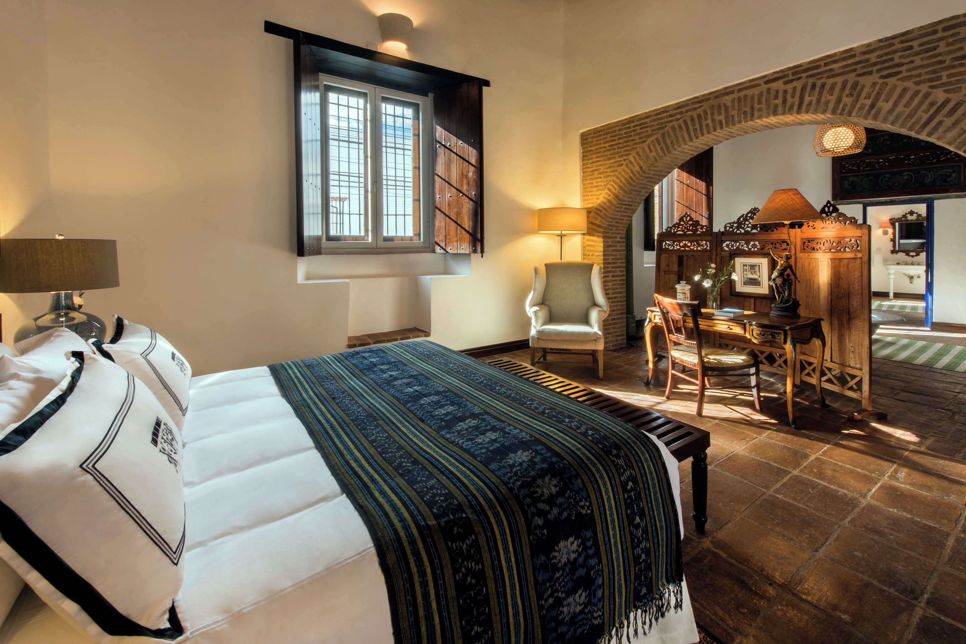 Ein Hotelzimmer mit Bett, Stuhl, Schreibtisch und Blick auf einen Außenbereich.