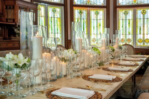 A long dining table set with candles, glassware, and place settings.
