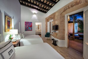 Une chambre d’hôtel avec deux lits, une télévision, un bureau avec une lampe et un tableau.