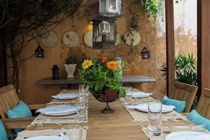 Een eettafel gedekt met borden, glazen en een bloemenstuk als decoratie.