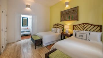 Habitación de hotel con dos camas, baño y pasillo.