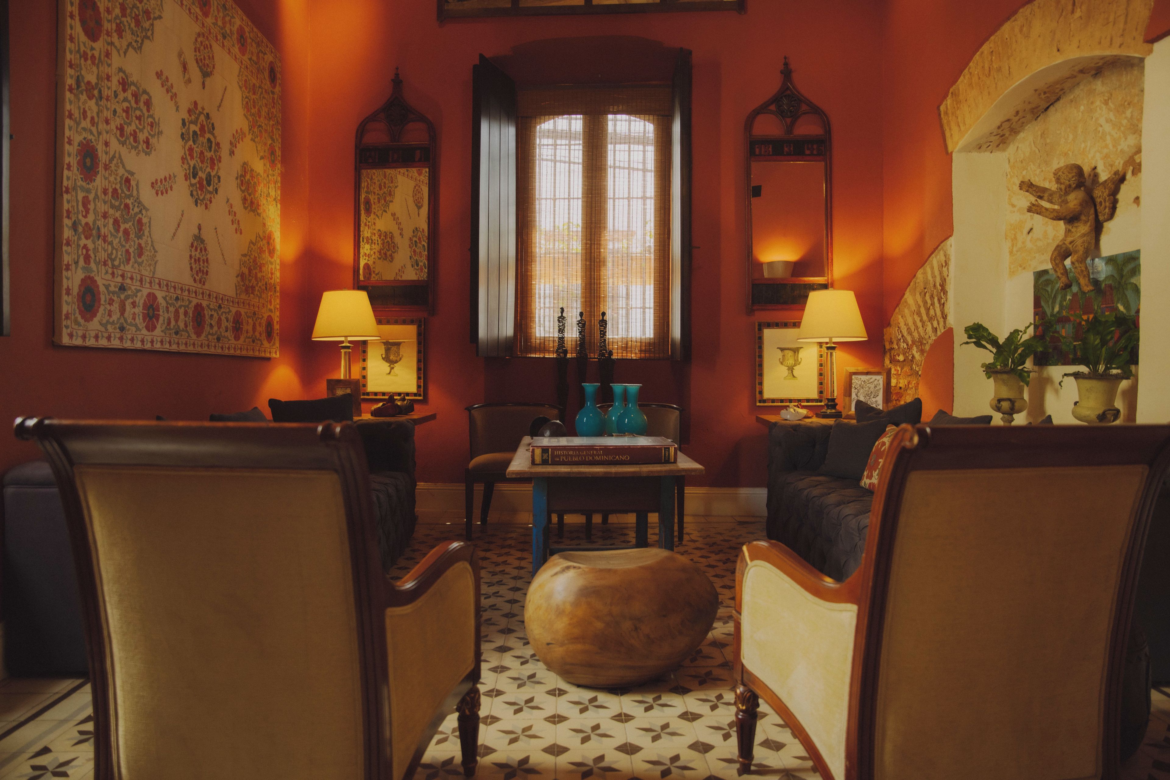 A room with a patterned floor, two armchairs, a table with a book, and two lamps.