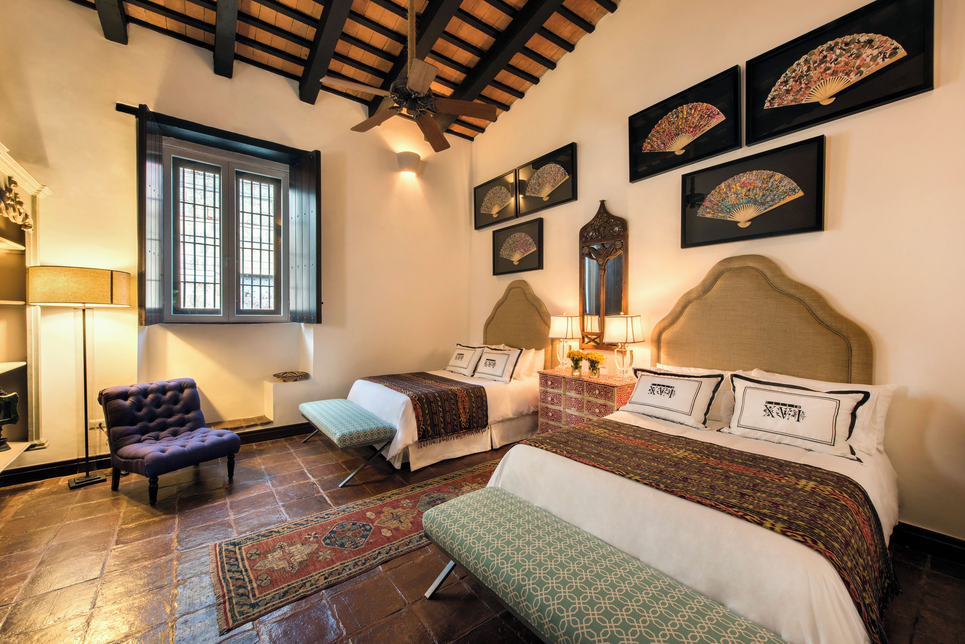 Een kamer met een bed, een stoel, een raam en kunst aan de muur.