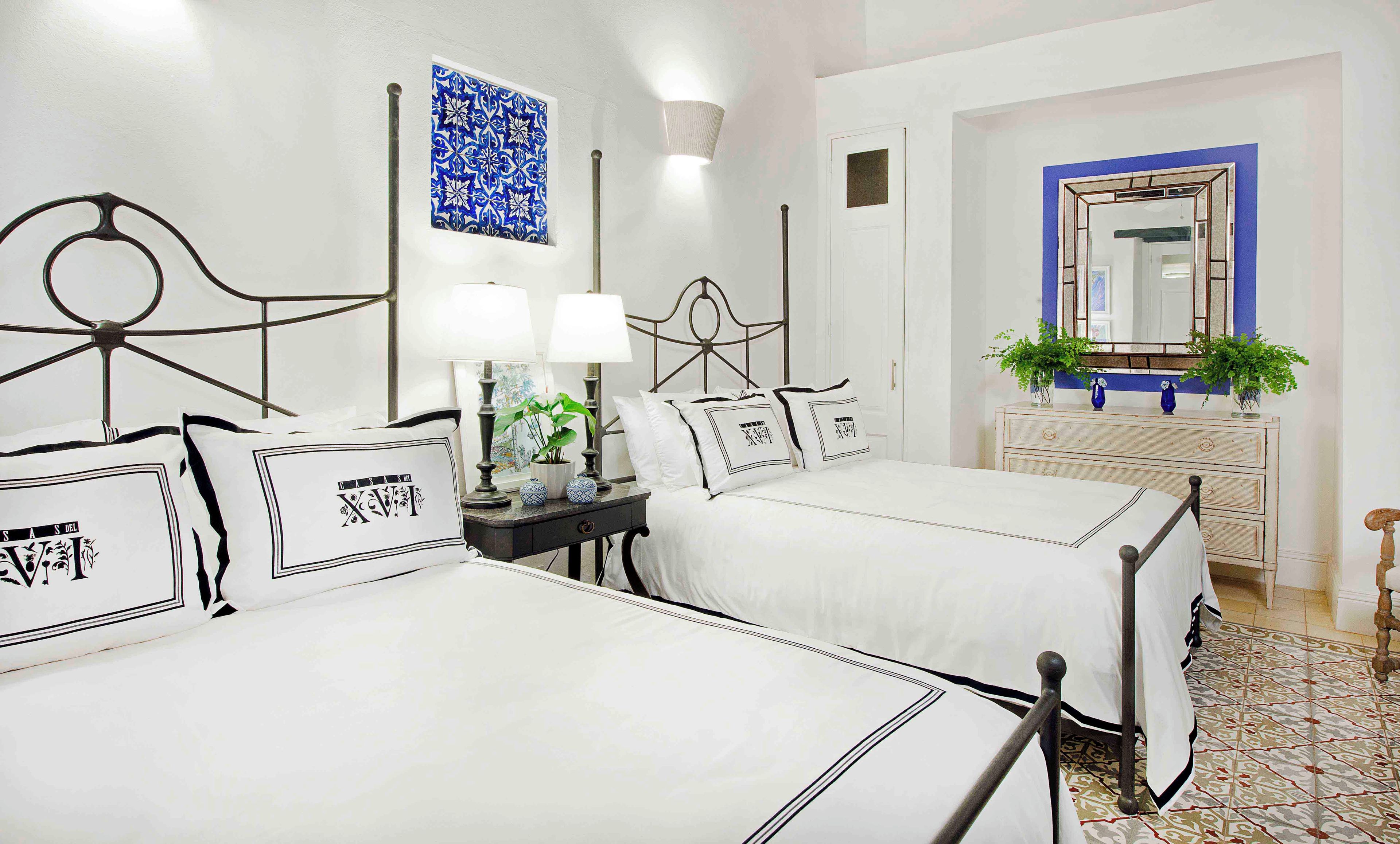 Une chambre d’hôtel avec deux lits, une table de chevet avec des lampes, une commode et un miroir.