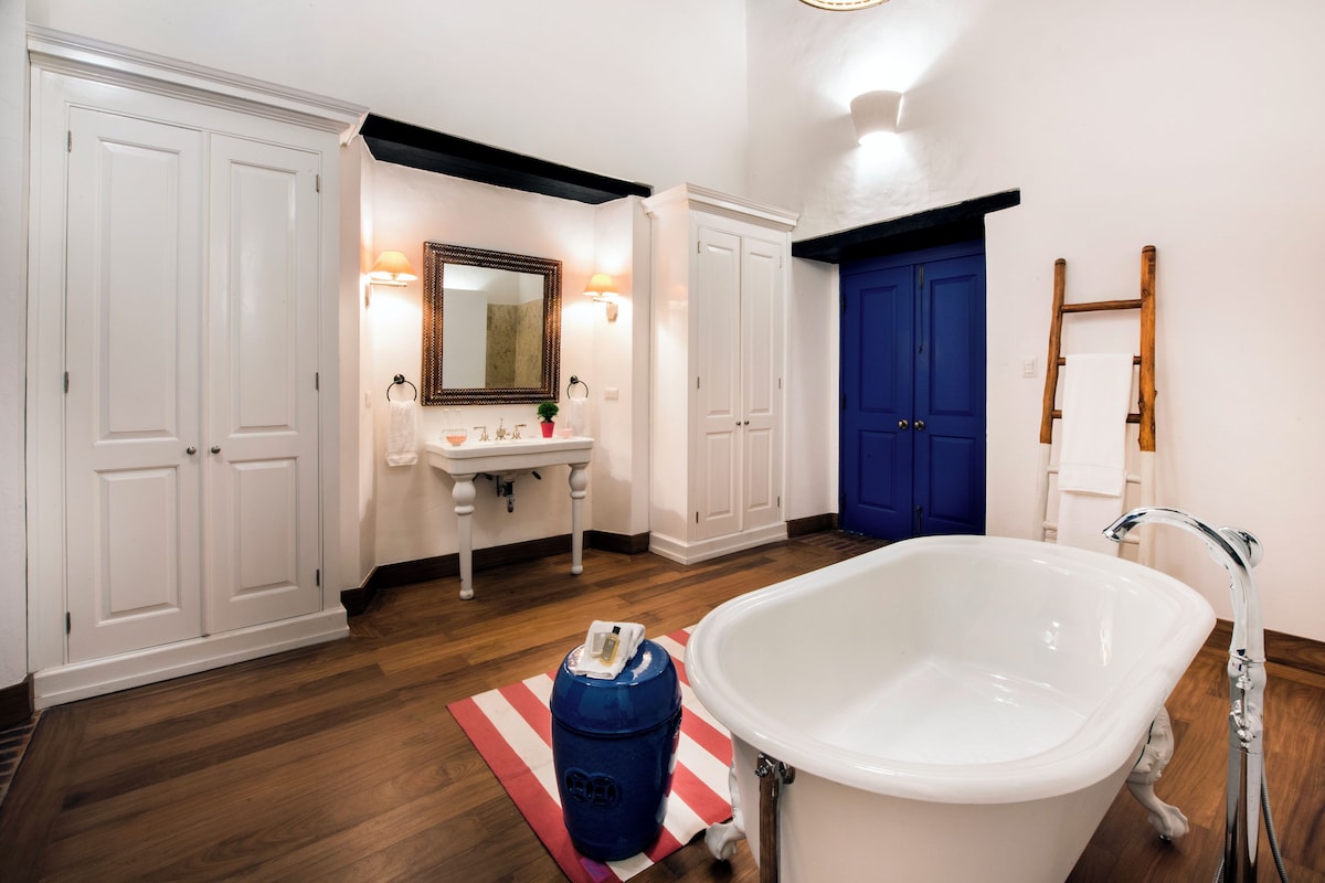 A bathroom with a white bathtub, a blue door, and a wooden ladder.