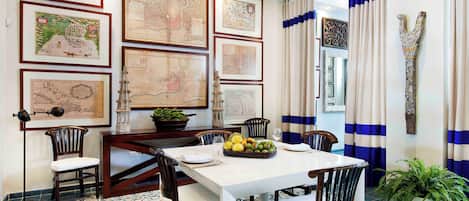 Un comedor con una mesa, sillas y varios mapas enmarcados en la pared.