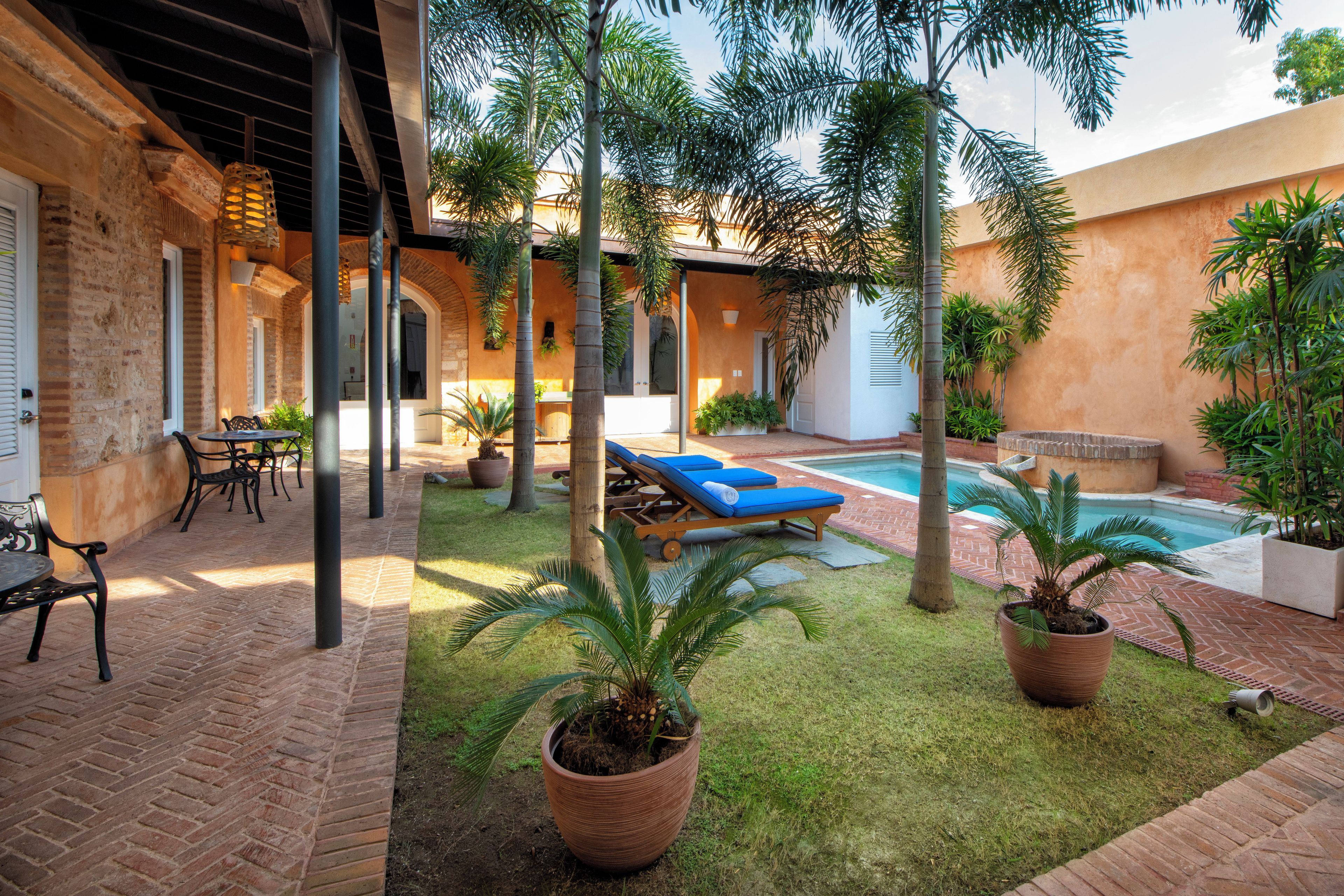 Pátio com piscina, cadeiras de descanso e plantas em vasos.