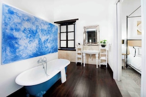 A bathroom with a freestanding bathtub, a large mirror, and a window.